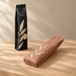 Matte black and terracotta side gusset bags with leaf artwork on a wooden table