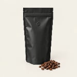 A matte black laminated stand-up coffee pouch with a centered one-way degassing valve beside roasted coffee beans