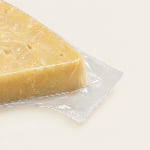 A transparent vacuum bag edge shows film hugging cheese and a clean continuous flat heat seal.